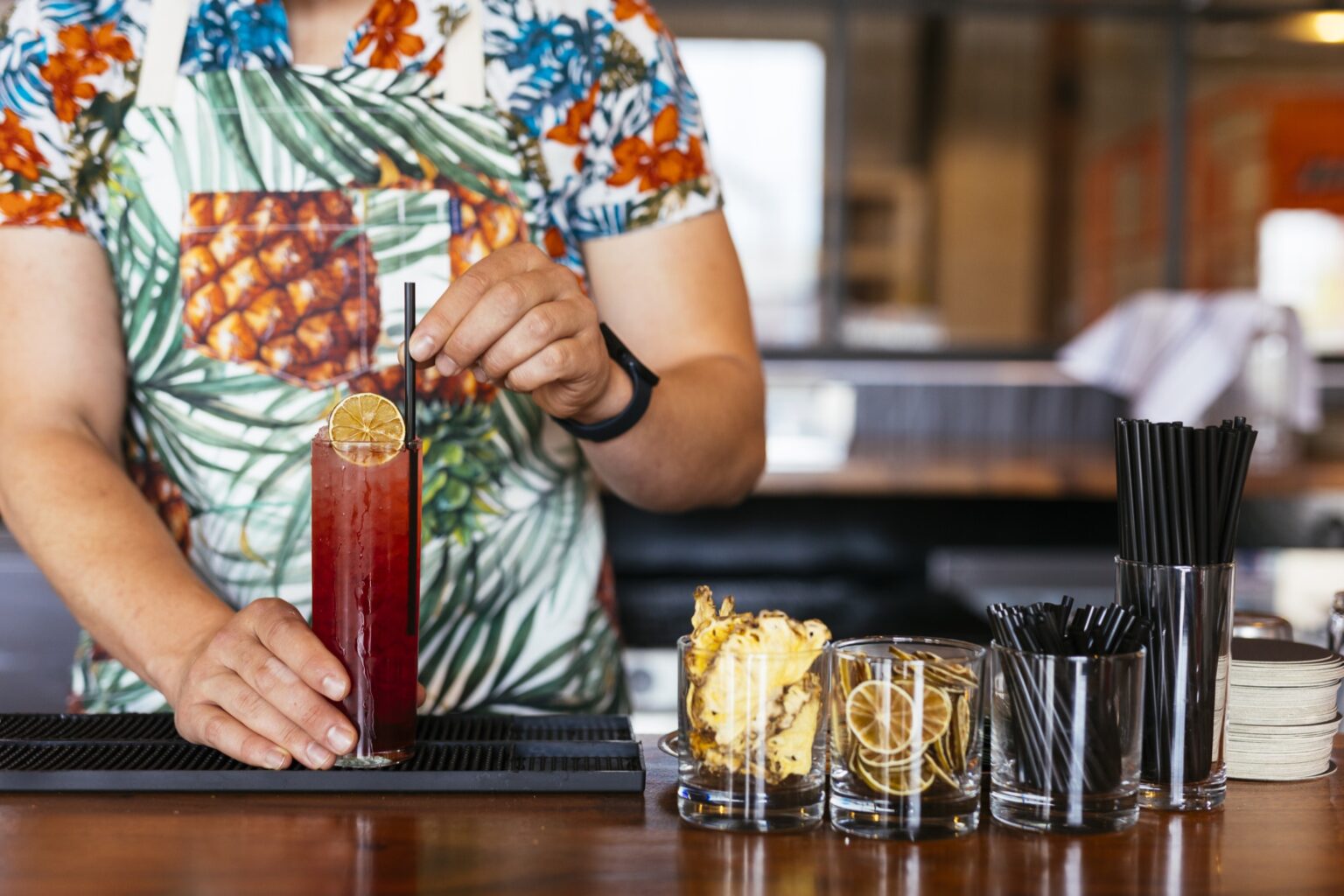 A deep red cocktail with a slice of fruit for garnish